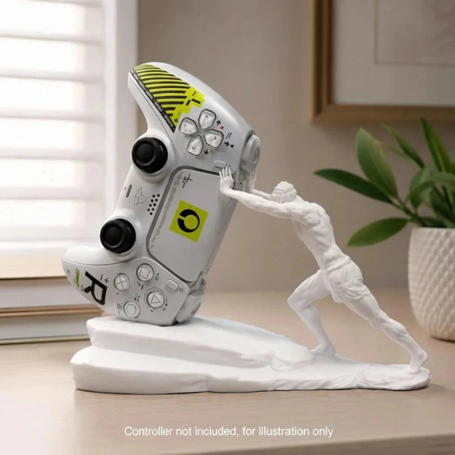 A white gaming figurine of a muscular man pushing a tilted silver and yellow video game controller on a matching white base, displayed on a wooden table in a home setting.