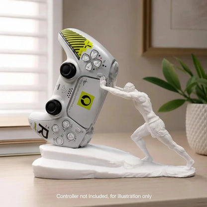 A white gaming figurine of a muscular man pushing a tilted silver and yellow video game controller on a matching white base, displayed on a wooden table in a home setting.