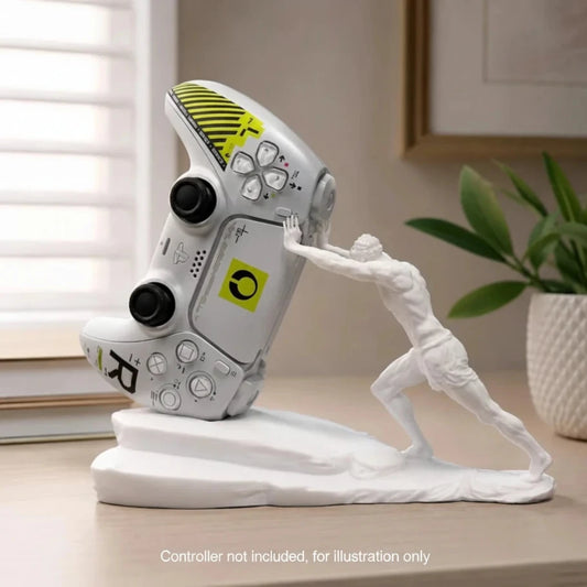 A white gaming figurine of a muscular man pushing a tilted silver and yellow video game controller on a matching white base, displayed on a wooden table in a home setting.