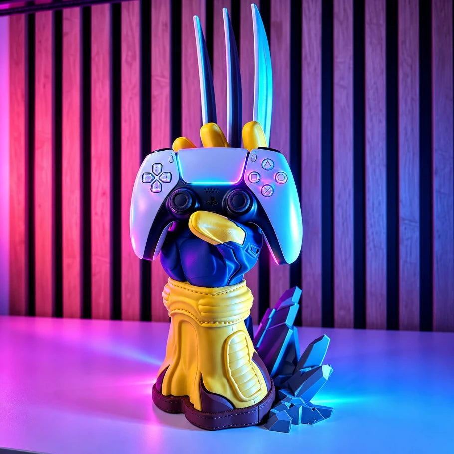 A PlayStation 5 console styled as a bird mascot wearing a gold and blue armored chest piece, with three tall blue claw-like antennas on top, displayed on a table against a purple and pink striped background.