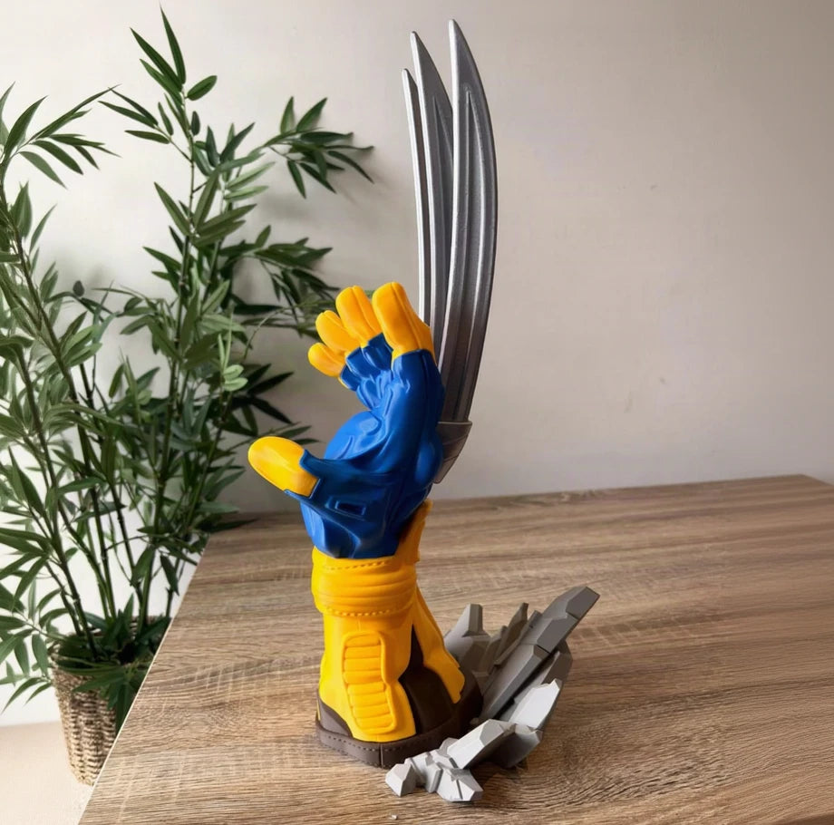 a breaker claw hand sculpture with a blue and yellow glove, metallic silver claws, and a gray cracked base, displayed on a wooden tabletop with a potted plant in the background.