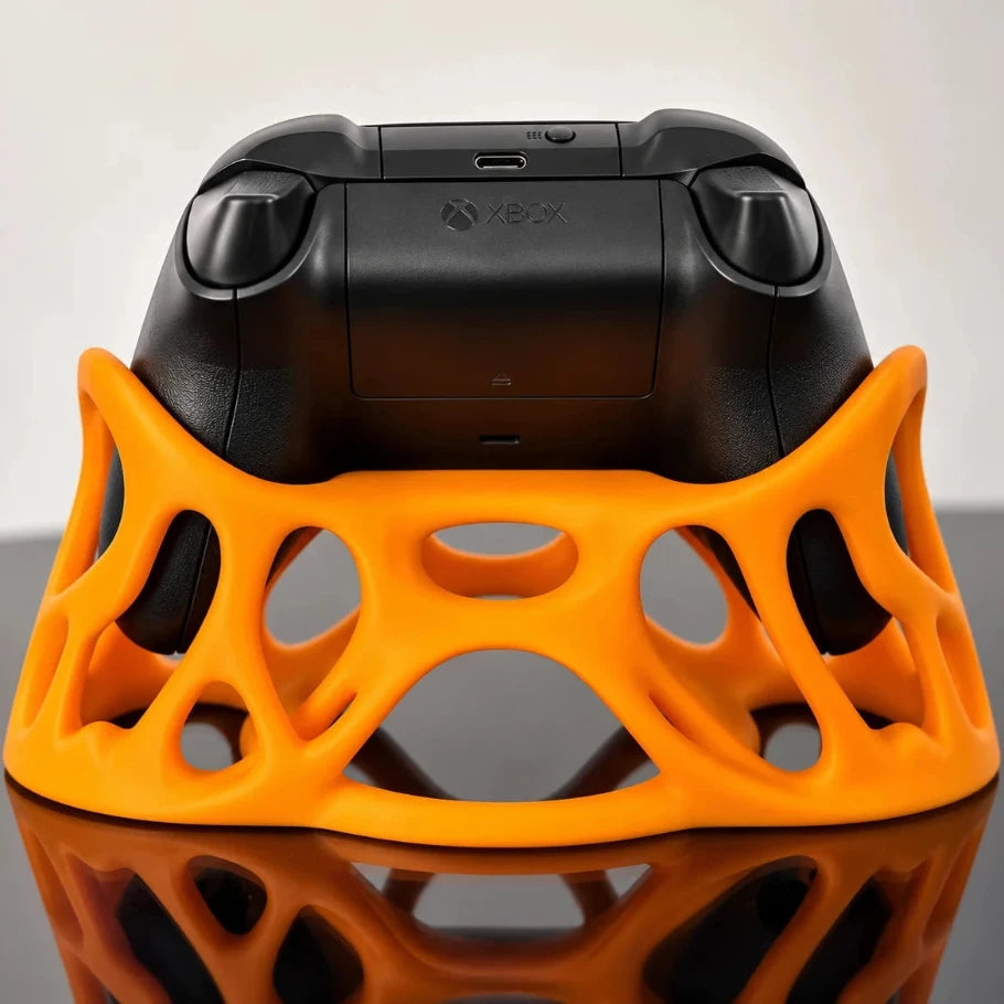rear view of an orange xbox controller stand holding a black xbox controller, showcasing its ergonomic grips and lattice structure