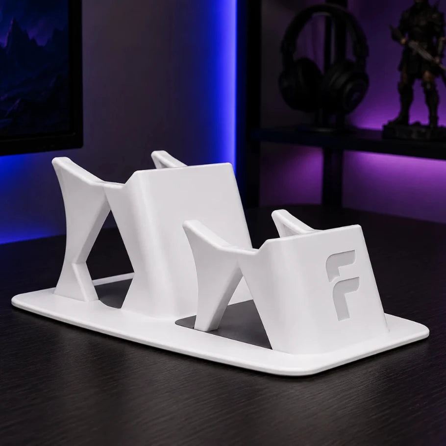 White electronic stand with a logo on a dark surface, with a gaming setup in the background.