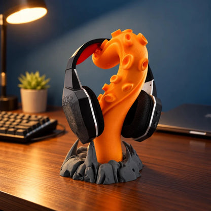 Orange 3D printed tentacle headphone holder displaying black and red gaming headphones on a sculpted dark grey rocky base.