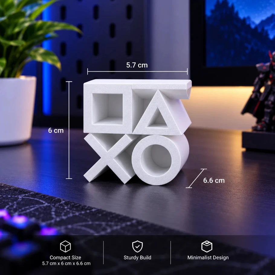 White PlayStation-themed decorative block with a square, triangle, cross, and circle design, shown on a desk with dimension labels (5.7 cm, 6 cm, 6.