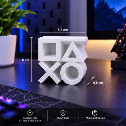 White PlayStation-themed decorative block with a square, triangle, cross, and circle design, shown on a desk with dimension labels (5.7 cm, 6 cm, 6.