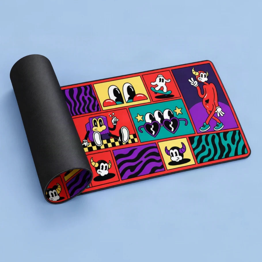 fictioo retro pop-art deskmat partially rolled to showcase its printed cartoon design, vibrant colors and black rubber backing against a blue background