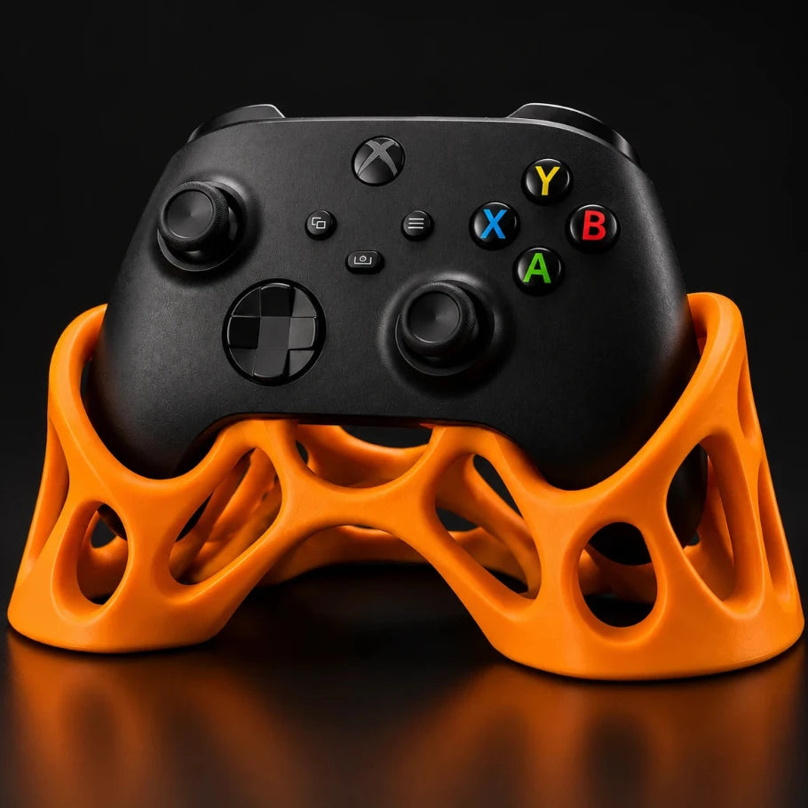 Orange Xbox controller stand with an organic lattice design holding a black Xbox controller against a dark studio background