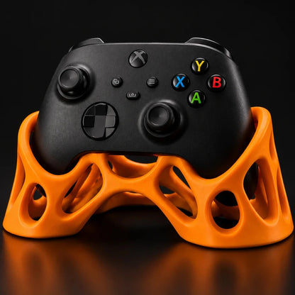 Orange Xbox controller stand with an organic lattice design holding a black Xbox controller against a dark studio background