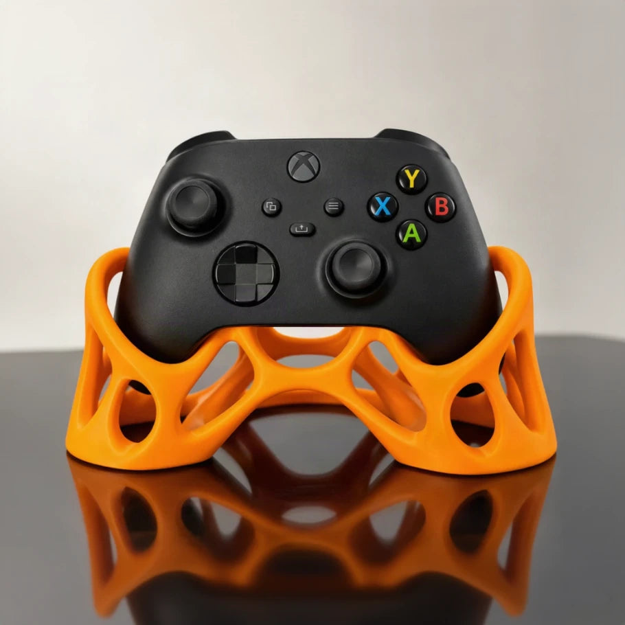 Front view of an orange Xbox controller holder with a black controller, featuring a sculptural lattice design