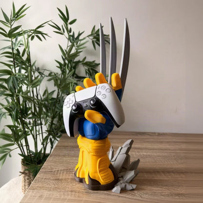 A stylized collectible figurine of Wolverine wearing a white PlayStation controller for a helmet, with his claws raised, standing on a wooden surface next to a potted plant.